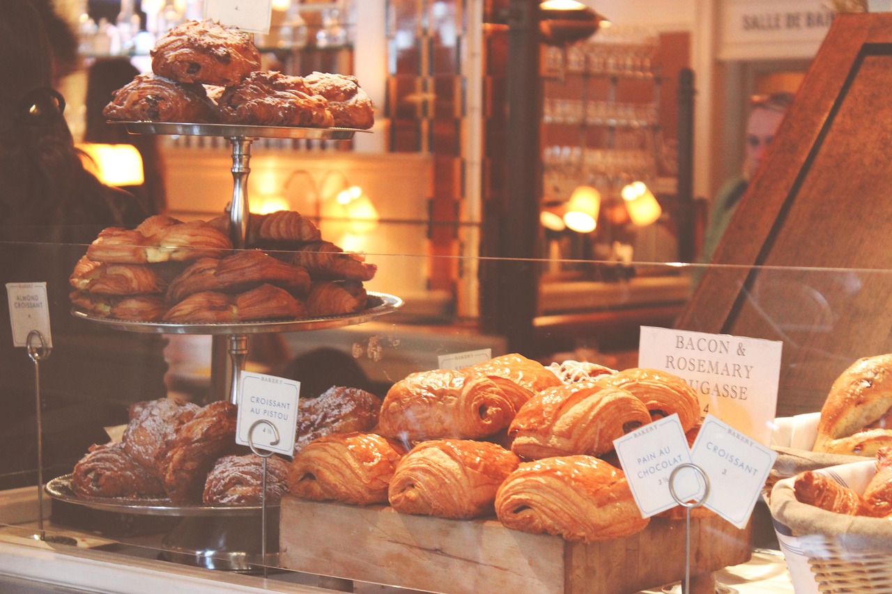 Croissants and pastries on stands in a bakery case